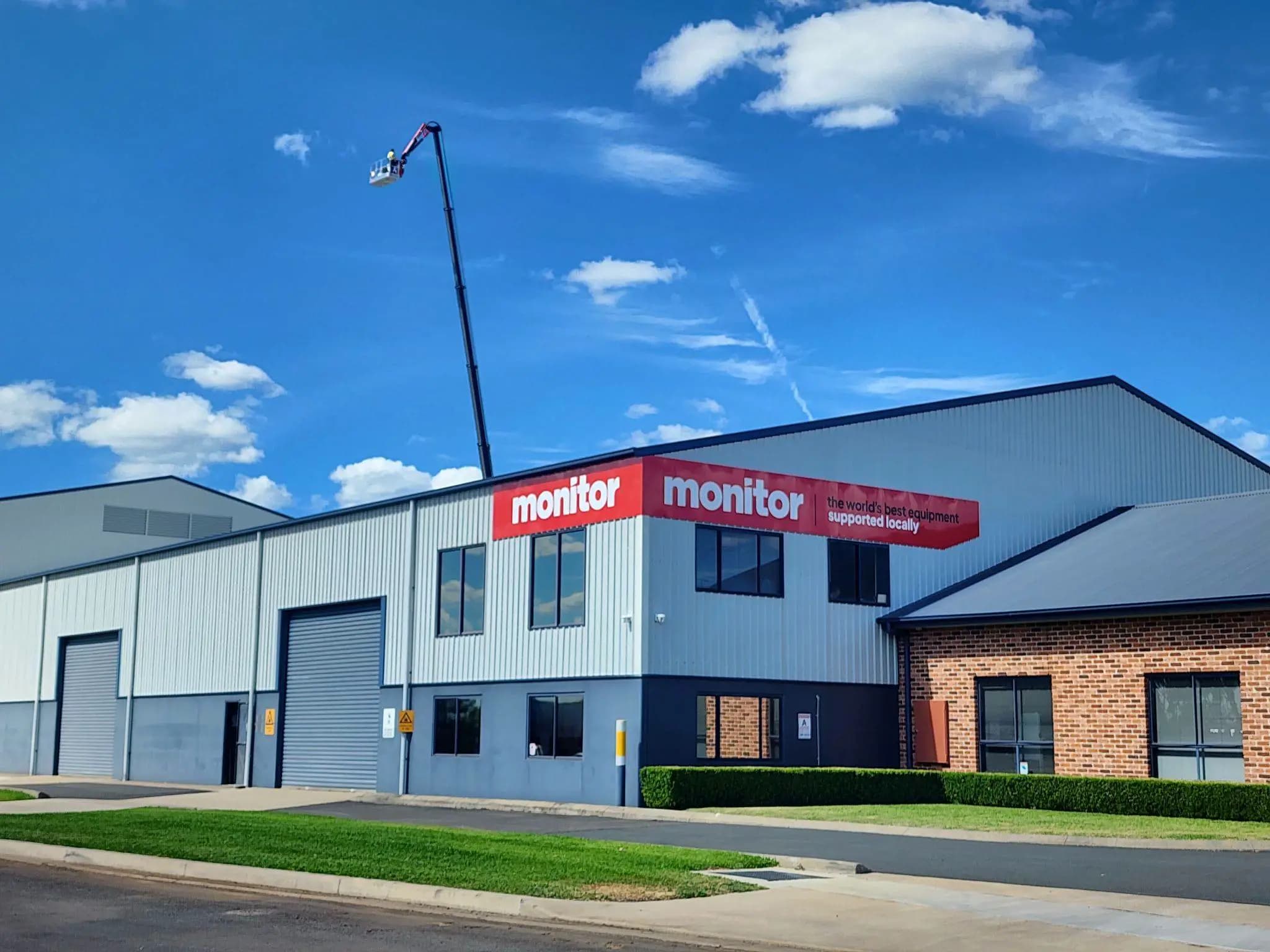 Hubarbeitsbühne an einem Gebäude mit einem Monitor-Schild daneben.