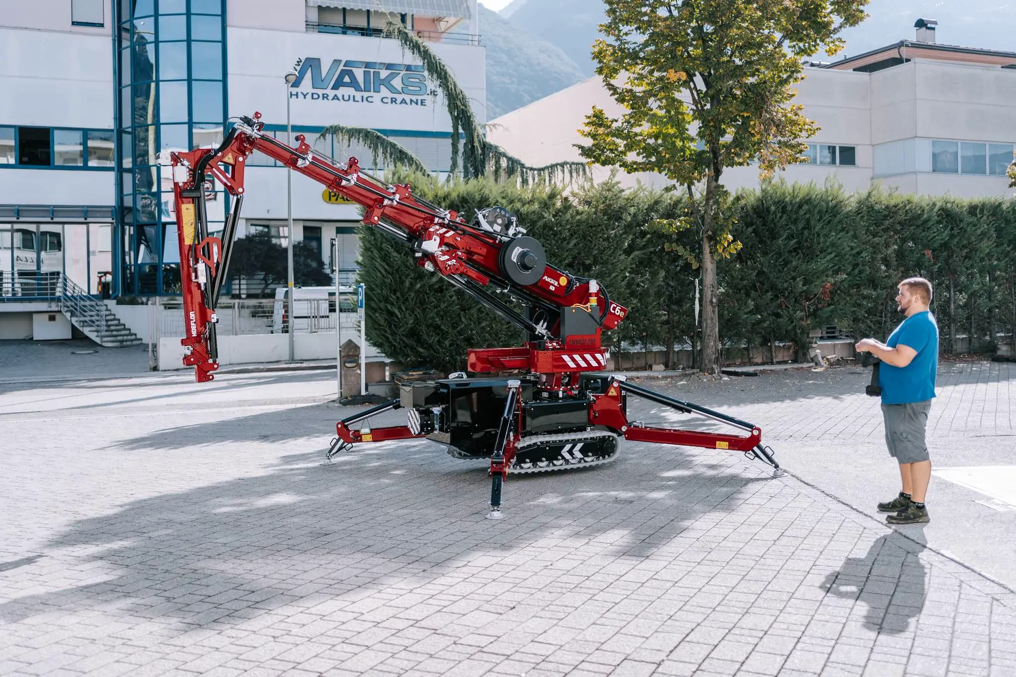 Hoeflon Kran in Aktion draußen, Mann steuert den Kran mit Fernbedienung.