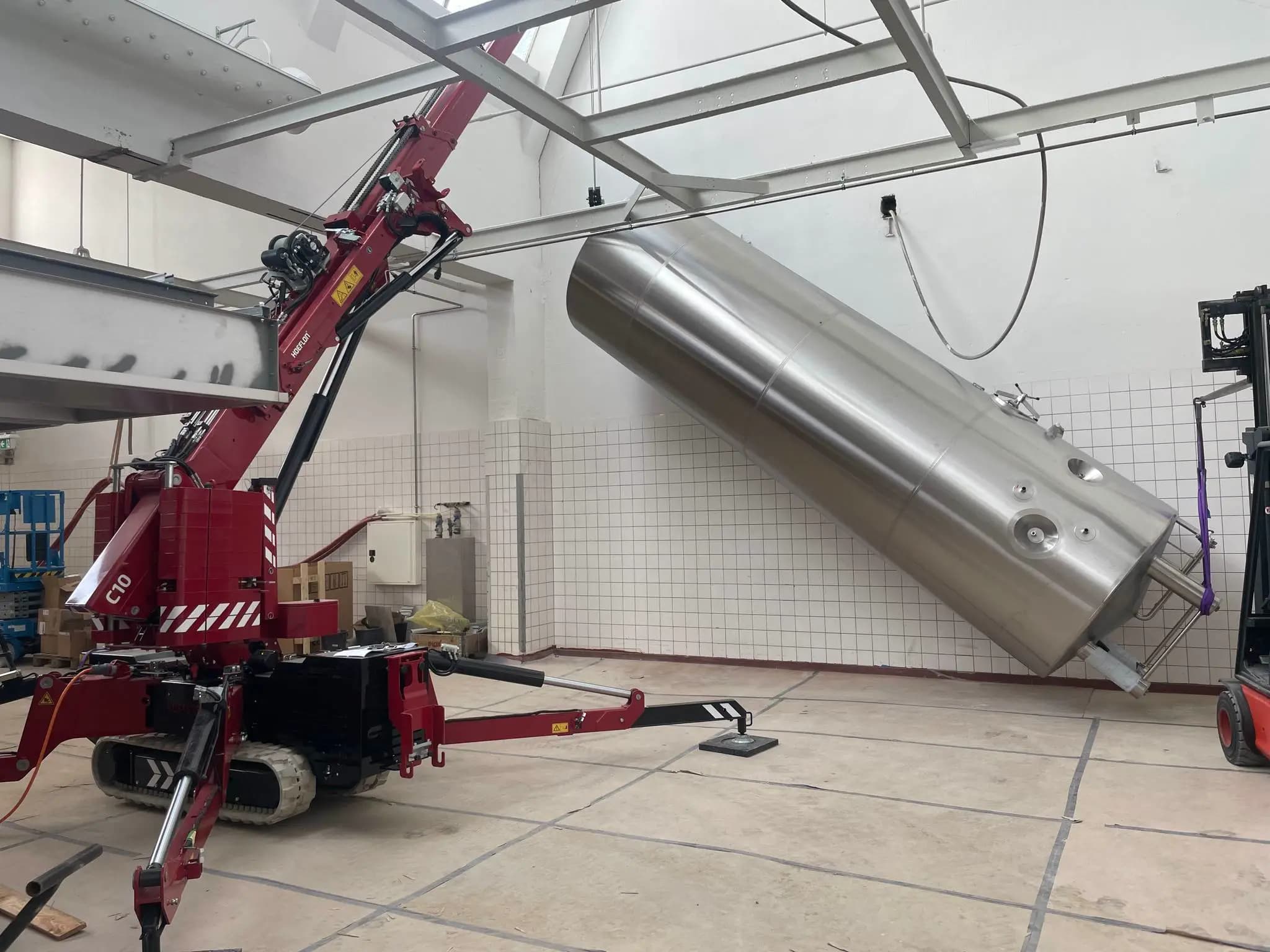Hoeflon C10 hebt einen großen Zylinder in einer Fabrikhalle.