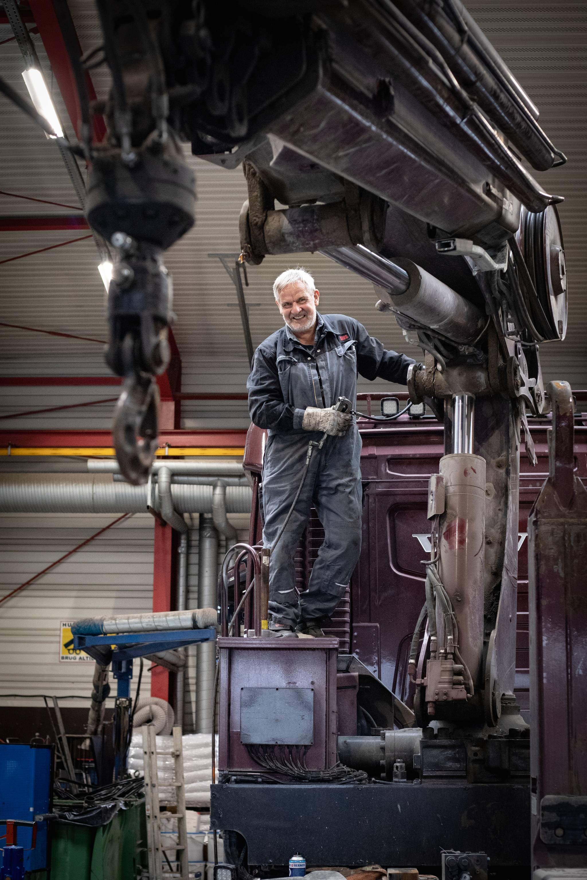 Mechaniker arbeitet an einem Kran in einer Werkstatt.