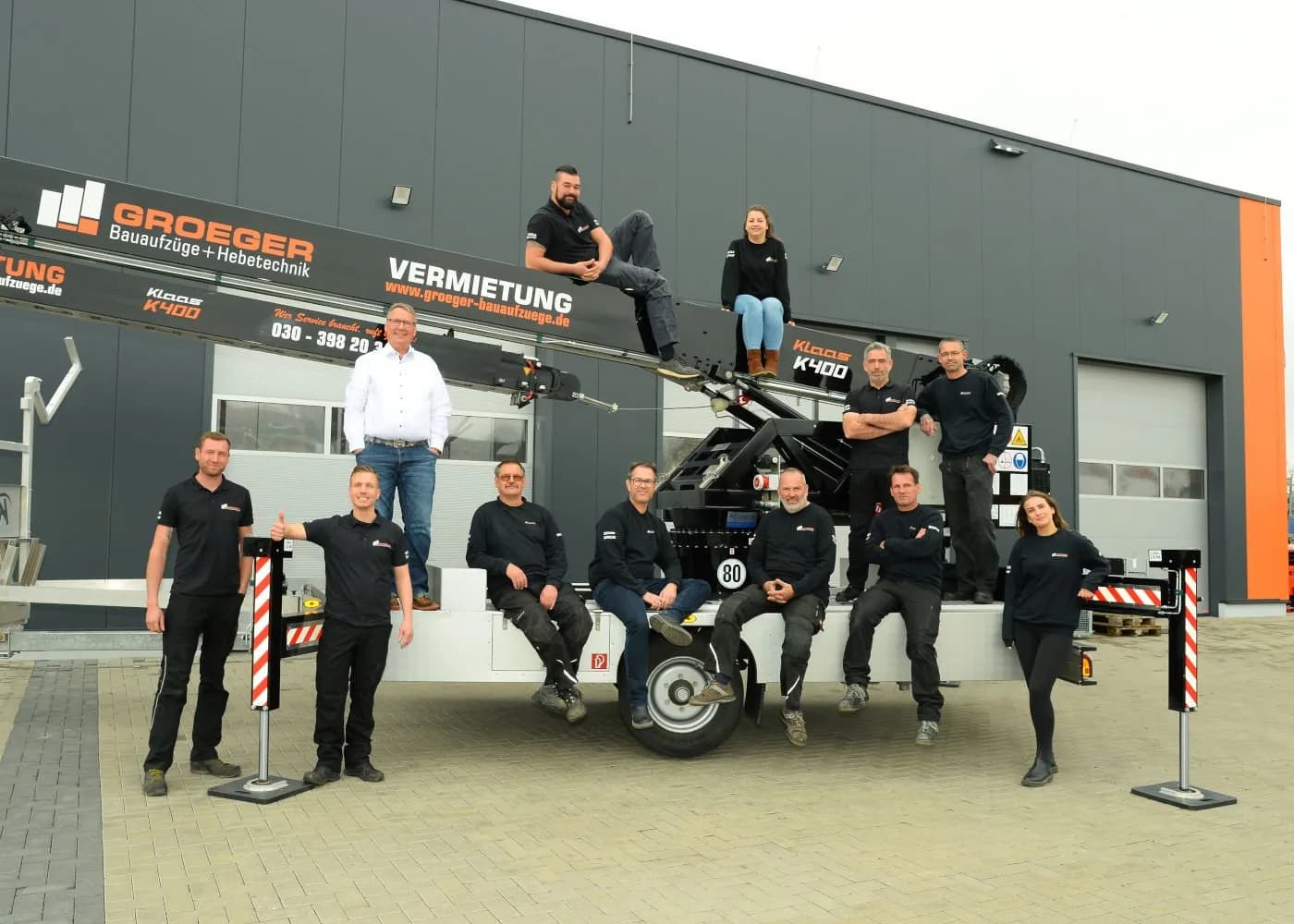 Teamfoto von Groeger Bauaufzüge mit Kran im Hintergrund.